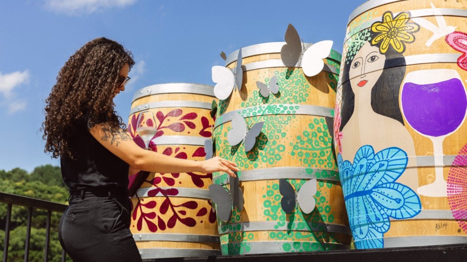 Foto mostra mulher e pipas de vinho pintadas