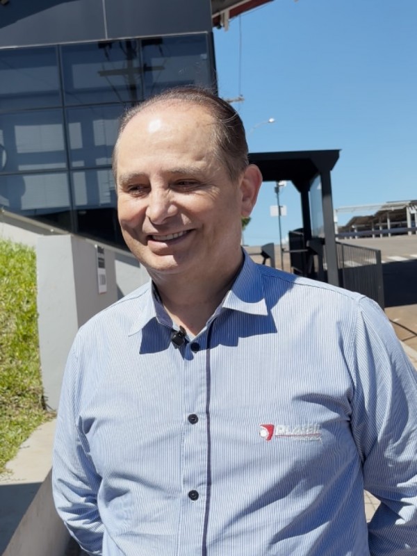 Foto mostra perfil de empresário, que sorri para alguém ao seu lado.