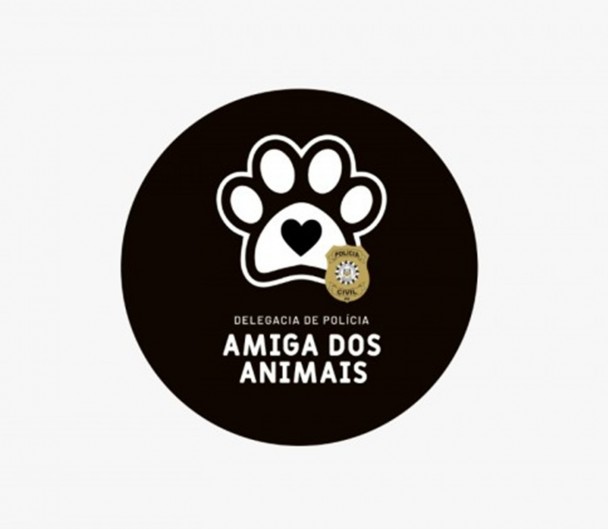 Selo redondo com fundo preto contendo desenho estilizado da planta de uma pata de animal, com o distintivo da Polícia Civil em um cando do desenho e abaixo as palavras Delegacia de Polícia Amiga dos Animais