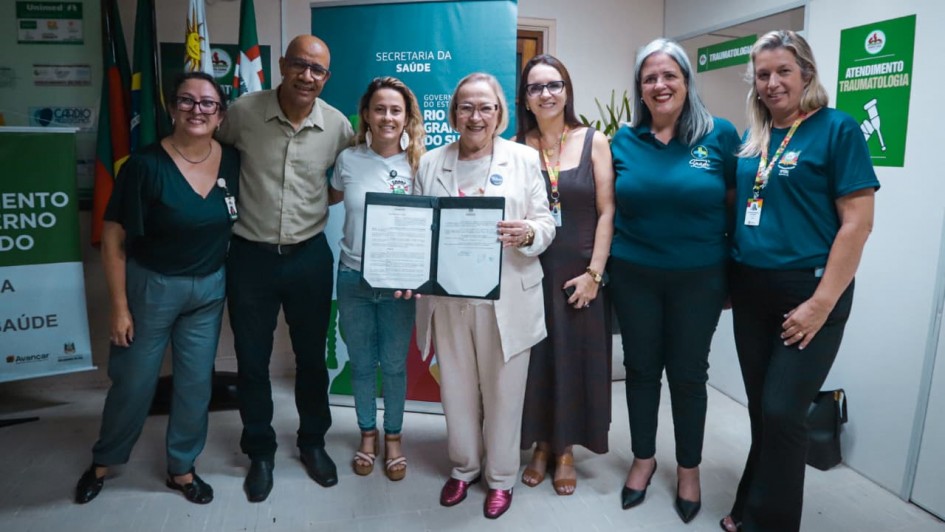 Foto mostra secret&aacute;ria Arita Bergmann e integrantes do hospital. Ela mostra um documento assinado.