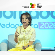 Reprodu&ccedil;&atilde;o da transmiss&atilde;o da live no Youtube. A imagem mostra a secret&aacute;ria da Educa&ccedil;&atilde;o sentada, falando ao microfone. Em uma miniatura, v&ecirc;-se a tradutora de Libras. Tamb&eacute;m se pode ler "Jornada Pedag&oacute;gica 2026 - Seduc RS" e a marca do Governo do Rio Grande do Sul.