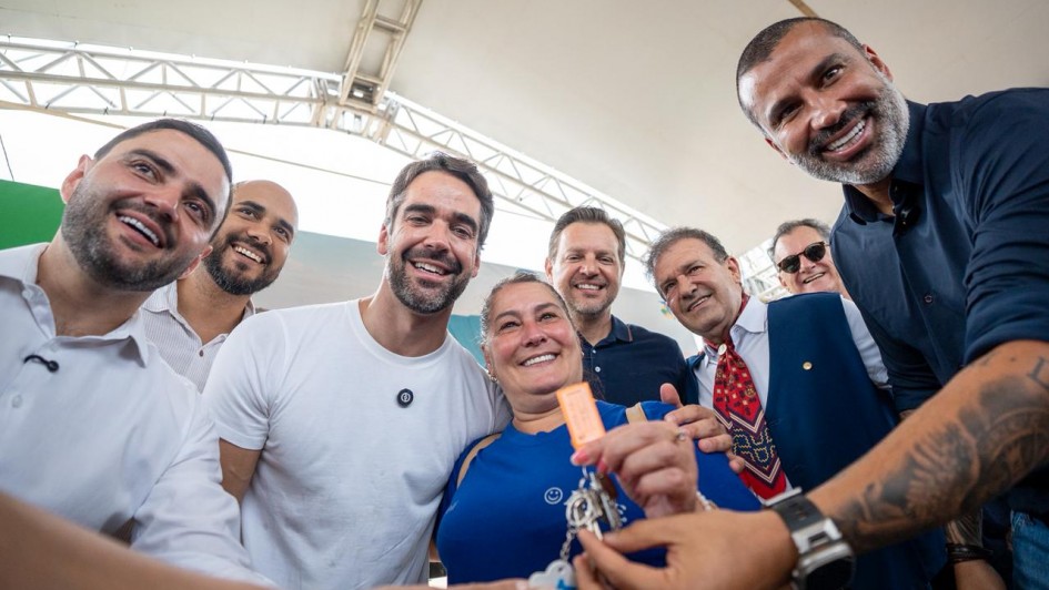 Um grupo de pessoas est&aacute; em p&eacute;, posando para a foto. Ao centro, uma mulher segura e exibe um molho de chaves, ao lado do governador Eduardo Leite e do vice-governador Gabriel Souza. 