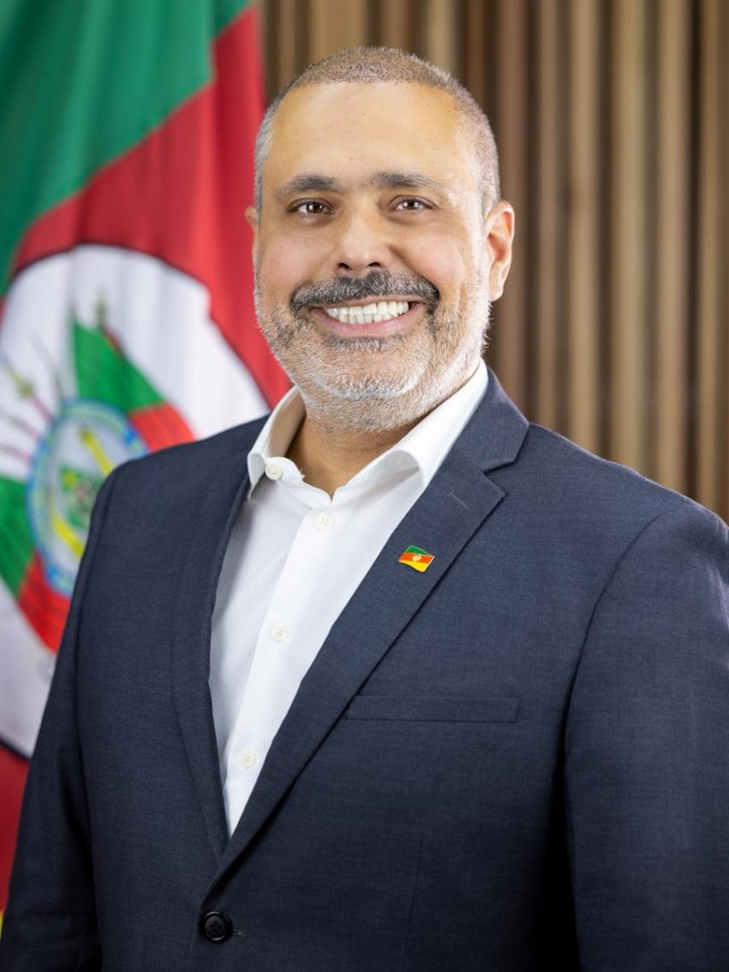 Homem em pose formal para foto em frente &agrave; bandeira do Rio Grande do Sul
