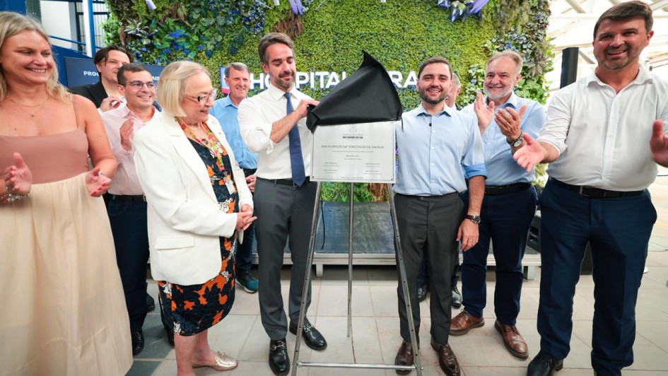 Governador Eduardo Leite, vice Gabriel Souza e secret&aacute;ria Arita em frente &agrave; placa de inaugura&ccedil;&atilde;o da obra. Outras autoridades aplaudem. 