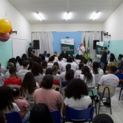 Foto mostra uma sala cheia de pessoas sentadas que acompanham um palestrante que est&aacute; de p&eacute; com um microfone. 