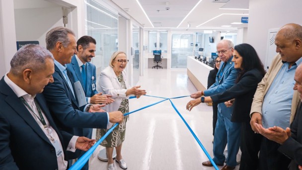Foto mostra secret&aacute;ria e autoridades descerrando fita azul que marca inaugura&ccedil;&atilde;o de unidade do Hospital Santa Clara. Ao fundo, uma sala com corredor branco, e espa&ccedil;os com divis&oacute;rias de vidro. 