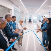 Foto mostra secret&aacute;ria e autoridades descerrando fita azul que marca inaugura&ccedil;&atilde;o de unidade do Hospital Santa Clara. Ao fundo, uma sala com corredor branco, e espa&ccedil;os com divis&oacute;rias de vidro. 
