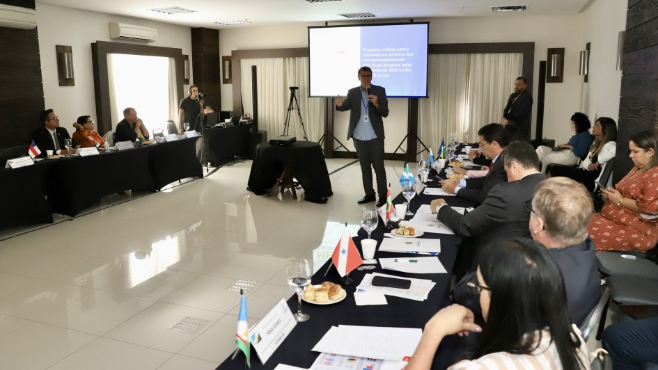 Foto mostra o secret&aacute;rio Gilmar Sossella falando aos outros secret&aacute;rios. Ele est&aacute; de p&eacute; ao microfone, os demais est&atilde;o sentados. 