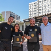 Ao centro, policiais penais Grasiele Shmaltz e Everton Muniz receberam reconhecimento pela bravura e presteza de sua conduta, das m&atilde;os de o secret&aacute;rio de Sistemas Penal e Socioeducativo, Jorge Pozzobom (D), e o superintendente da Pol&iacute;cia Penal, Sergio Dalcol (E)