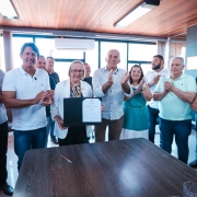 Foto mostra secret&aacute;ria Arita Bergmann segurando um documento. Outras pessoas est&atilde;o na volta e aplaudem o ato.