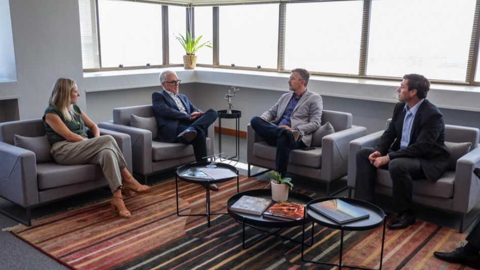 Esta &eacute; uma descri&ccedil;&atilde;o detalhada da imagem para fins de acessibilidade:

Descri&ccedil;&atilde;o da Imagem
A fotografia registra uma reuni&atilde;o institucional em um escrit&oacute;rio moderno, focada no combate &agrave; sonega&ccedil;&atilde;o fiscal.

Participantes: Quatro pessoas (tr&ecirc;s homens e uma mulher) est&atilde;o sentadas em poltronas individuais cinzas, dispostas em formato de "U" para facilitar o di&aacute;logo.

&Agrave; esquerda, uma mulher de cabelos loiros veste uma blusa verde escura e cal&ccedil;as bege.

Ao centro-esquerda, um homem de cabelos grisalhos e &oacute;culos veste um terno azul marinho e gesticula enquanto fala.

Ao centro-direita, outro homem de cabelos grisalhos veste um palet&oacute; cinza claro sobre uma camisa azul.

&Agrave; direita, um homem de cabelos escuros veste um terno preto e observa a conversa.

Ambiente:

O grupo est&aacute; sobre um tapete listrado em tons de marrom, laranja e bege.

&Agrave; frente deles, h&aacute; tr&ecirc;s pequenas mesas de centro circulares pretas; sobre elas, veem-se livros de arte/fotografia e alguns documentos.

Ao fundo, grandes janelas de vidro ocupam toda a extens&atilde;o da parede, revelando uma vista urbana clara, embora os detalhes externos estejam ofuscados pela luminosidade. Um pequeno vaso com uma planta verde est&aacute; posicionado no parapeito da janela.

Contexto: De acordo com o t&iacute;tulo do arquivo, a imagem retrata a entrega de dados pela Receita Estadual ao Minist&eacute;rio P&uacute;blico sobre casos de sonega&ccedil;&atilde;o que superam R$ 217 milh&otilde;es.

Clima: A ilumina&ccedil;&atilde;o &eacute; natural e abundante, conferindo um aspecto s&oacute;brio e profissional ao encontro.