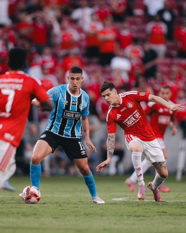 Disputa de lance entre jogadores do Grêmio e do Inter no Gre-Nal deste domingo, com camisetas estampando mensagem contra a violência de gênero