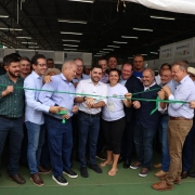 Esta &eacute; uma descri&ccedil;&atilde;o detalhada da imagem para fins de acessibilidade:

Descri&ccedil;&atilde;o da Imagem
A fotografia registra a cerim&ocirc;nia de inaugura&ccedil;&atilde;o do Pavilh&atilde;o da Agricultura Familiar durante a feira Expodireto Cotrijal.

A&ccedil;&atilde;o Central: No centro da imagem, um grande grupo de homens e uma mulher est&atilde;o reunidos para o ato simb&oacute;lico de corte da fita inaugural. A fita &eacute; de cor verde vibrante. V&aacute;rias m&atilde;os seguram e tensionam a fita enquanto o Governador Eduardo Leite (ao centro, de camisa branca e cal&ccedil;a jeans) se prepara para cort&aacute;-la.

Os Participantes:

O grupo &eacute; composto por cerca de 20 pessoas, a maioria homens vestindo camisas sociais de tons claros (azul e branco) ou camisetas de eventos.

&Agrave; direita do Governador, uma mulher de camiseta branca e cabelos presos sorri enquanto segura a fita.

Os participantes apresentam express&otilde;es de entusiasmo e alegria, celebrando o momento.

O Ambiente:

A cena ocorre sob a estrutura de um pavilh&atilde;o com teto de metal aparente e ilumina&ccedil;&atilde;o por calhas de LED.

Ao fundo, &agrave; direita, veem-se estandes brancos com logotipos da EMATER/RS e da Secretaria de Desenvolvimento Rural.

O ch&atilde;o do pavilh&atilde;o &eacute; pintado de verde escuro.

Contexto: Segundo o t&iacute;tulo do arquivo, o espa&ccedil;o destaca a diversidade da produ&ccedil;&atilde;o rural do Rio Grande do Sul no contexto da feira Expodireto Cotrijal.