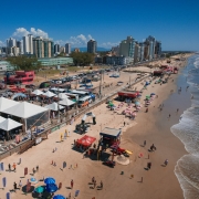 Foto a&eacute;rea mostra tendas da Opera&ccedil;&atilde;o Ver&atilde;o Total na beira da praia com mar em perspectiva.