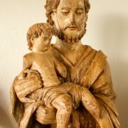 A imagem mostra uma escultura sacra em madeira, característica do estilo barroco missioneiro.