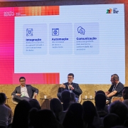 Foto mostra palestrantes sentados diante da plateia.