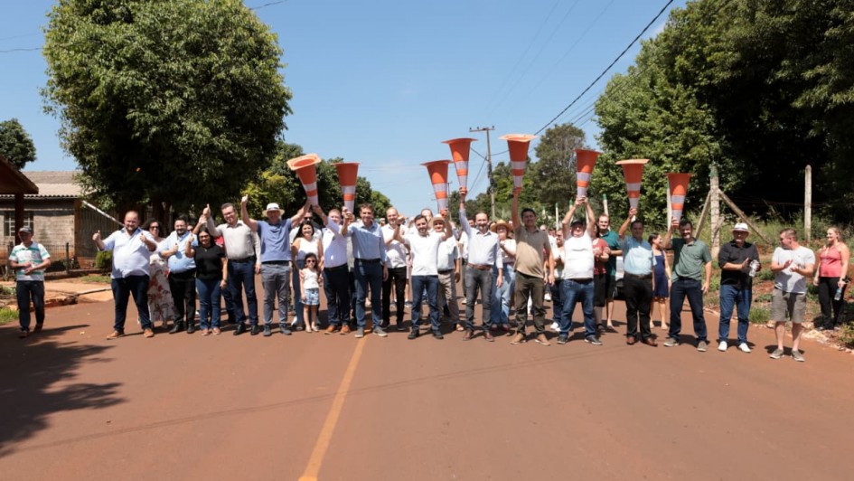 V&aacute;rias pessoas lado a lado em uma estrada asfaltada seguram acima de suas cabe&ccedil;as cones de tr&acirc;nsito simbolizando a libera&ccedil;&atilde;o do tr&acirc;nsito na via