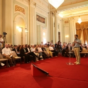 Governador Eduardo Leite discursando em p&eacute;, diante da plateia, no Pal&aacute;cio Piratini. 