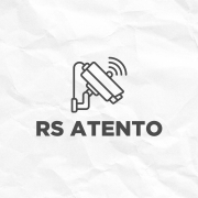 Fundo claro com textura que lembra papel amassado. No centro, h&aacute; um &iacute;cone de uma c&acirc;mera de vigil&acirc;ncia inclinada, com tr&ecirc;s linhas curvas ao lado indicando que est&aacute; transmitindo ou detectando movimento. Abaixo do &iacute;cone, est&aacute; escrito em letras grandes e escuras: &ldquo;RS ATENTO&rdquo;.

No canto inferior direito, aparece o logotipo do Governo do Estado do Rio Grande do Sul, com tr&ecirc;s silhuetas humanas sobrepostas nas cores verde, vermelho e amarelo, ao lado do texto institucional.