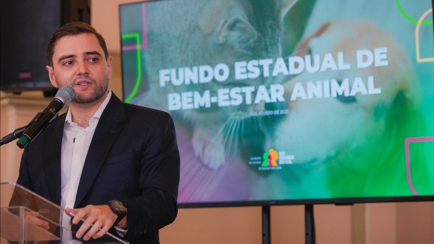 Foto mostra o vice-governador Gabriel Souza discursando no p&uacute;lpito. Atr&aacute;s dele, h&aacute; uma tela com um t&iacute;tulo "Fundo Estadual de Bem-Estar Animal.