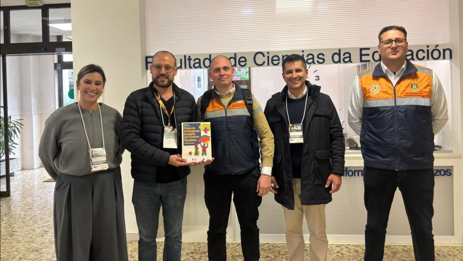 Foto mostra comitiva. S&atilde;o quatro homens e uma mulher. Dois deles est&atilde;o com coletes laranjas e azuis da Defesa Civil.