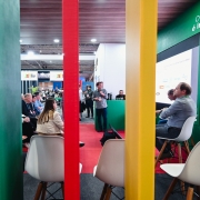 Foto mostra painel realizado no espa&ccedil;o do governo do Estado com painelistas e p&uacute;blico sentado. A cena &eacute; registrada atr&aacute;s de tr&ecirc;s pilares coloridos nas cores do Rio Grande do Sul, que est&atilde;o em primeiro plano. 