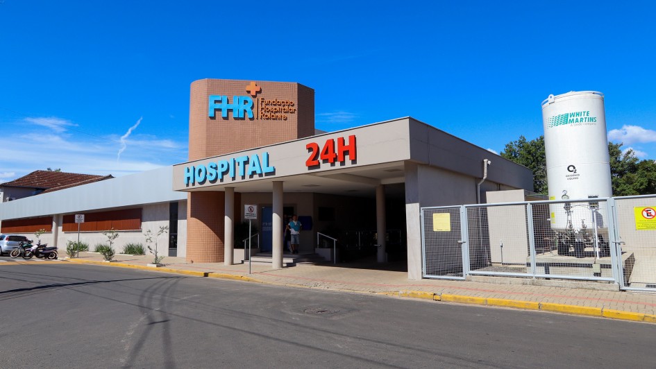 Fachada da Funda&ccedil;&atilde;o Hospitalar Rolante, com arquitetura moderna, fachada em tons claros e destaque para a identifica&ccedil;&atilde;o &ldquo;HOSPITAL 24H&rdquo; em letras grandes. 