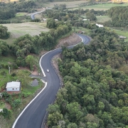 Vista a&eacute;rea de uma rodovia asfaltada recentemente, com tra&ccedil;ado sinuoso atravessando &aacute;rea rural.