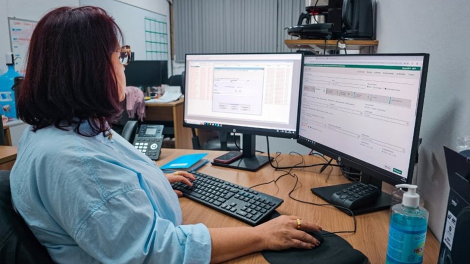 Foto mostra m&eacute;dica atendendo remotamente. Ela est&aacute; sentada em frente a um computador com dois monitores. 