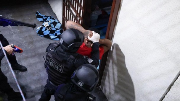 Esta &eacute; uma descri&ccedil;&atilde;o da imagem "Pol&iacute;cia Penal do RS participa de nova fase de opera&ccedil;&atilde;o contra comunica&ccedil;&otilde;es il&iacute;citas em apoio &agrave; estrat&eacute;gia nacional.jpeg" para fins de acessibilidade:

A fotografia em plano m&eacute;dio captura um policial penal de costas, em meio a uma galeria prisional vazia.

O Policial: Posicionado no centro-direita do quadro, o policial veste o uniforme operacional preto. Nas costas de sua camiseta, destaca-se a inscri&ccedil;&atilde;o "POL&Iacute;CIA PENAL" em letras brancas grandes, com a frase "RIO GRANDE DO SUL" logo abaixo em letras amarelas menores. Ele utiliza um cintur&atilde;o t&aacute;tico preto completo com diversos acess&oacute;rios.

O Ambiente:

O policial caminha ou observa um corredor longo e estreito de uma galeria prisional.

&Agrave; esquerda, estende-se uma sequ&ecirc;ncia de portas de celas feitas de grades de ferro pintadas de amarelo, todas fechadas.

O ch&atilde;o &eacute; de concreto cinza e as paredes s&atilde;o de blocos de concreto aparentes.

A ilumina&ccedil;&atilde;o &eacute; artificial, vinda de l&acirc;mpadas no teto, criando um contraste de luz e sombra ao longo do corredor.

A imagem reflete uma atmosfera de seguran&ccedil;a, fiscaliza&ccedil;&atilde;o e rotina operacional dentro de um estabelecimento prisional.