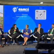 A imagem mostra um painel de discuss&atilde;o em um evento, com participantes sentados em palco usando fones e microfones, diante de um tel&atilde;o azul com informa&ccedil;&otilde;es do Congresso Ambiental.
