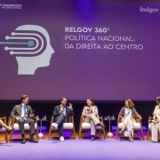 Foto de um palco com seis palestrantes sentados em poltronas. O governador do RS est&aacute; ao centro. Ao fundo, em um painel l&ecirc;-se "RELGOV 360&ordm; Pol&iacute;tica Nacional: da direita ao centro".