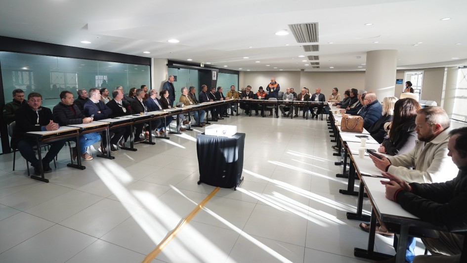 Foto mostra sala da reuni&atilde;o da Defesa Civil com a Famurs. Todos est&atilde;o dispostos com suas mesas em formato de U.