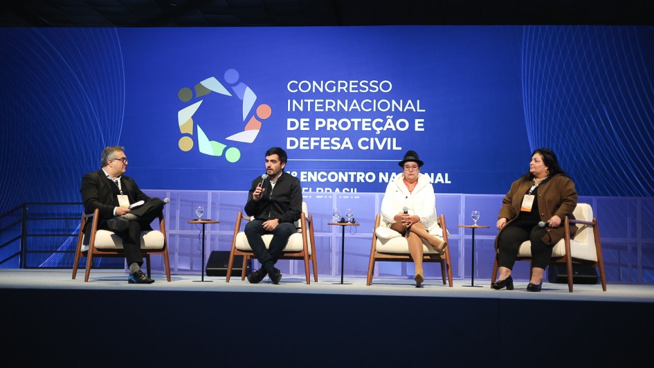 A imagem mostra um palco com quatro palestrantes sentados. Ao fundo, em um painel, l&ecirc;-se "Congresso Internacional de Prote&ccedil;&atilde;o e Defesa Civil". 