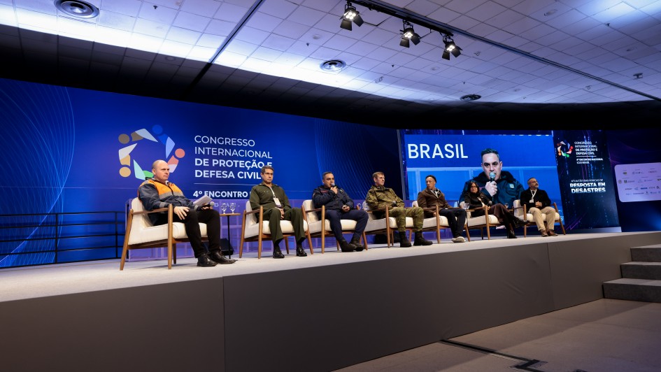 A imagem mostra um palco com oito palestrantes sentados diante de um painel onde se l&ecirc; "Congresso Internacional de Prote&ccedil;&atilde;o e Defesa Civil". 