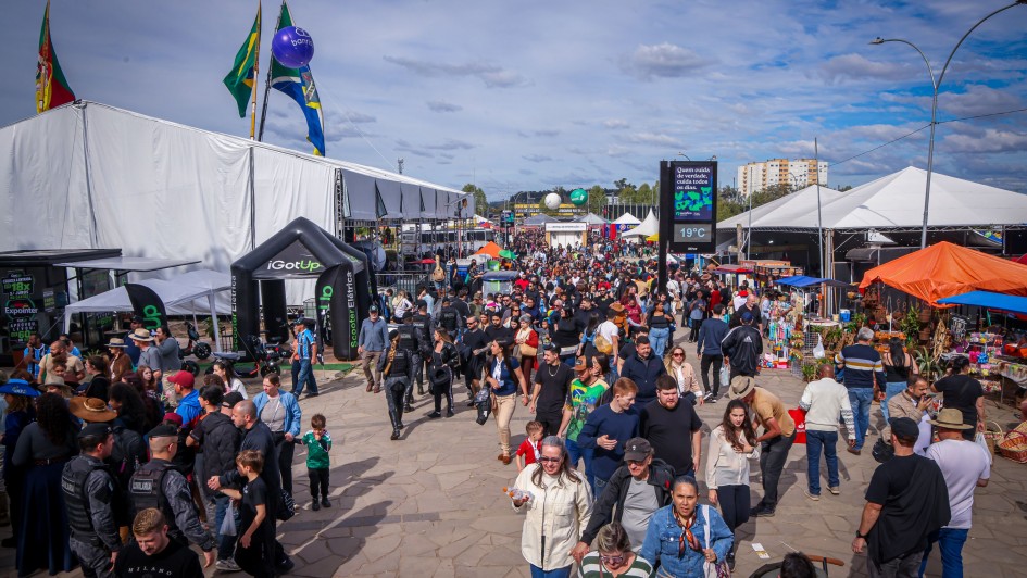 Imagem mostra grande p&uacute;blico na principal entrada da Expointer, com v&aacute;rios toldos de tendas nas laterais.