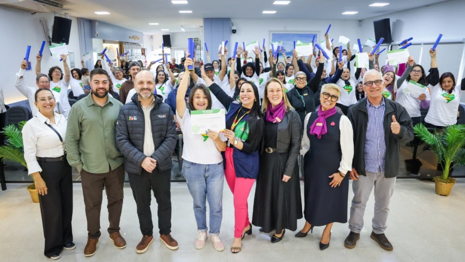 Foto mostra grupo de formandos e autoridades posando todos juntos. Os alunos, ao fundo, levantam os canudos de formatura. Todos parecem estar vibrando com o momento.