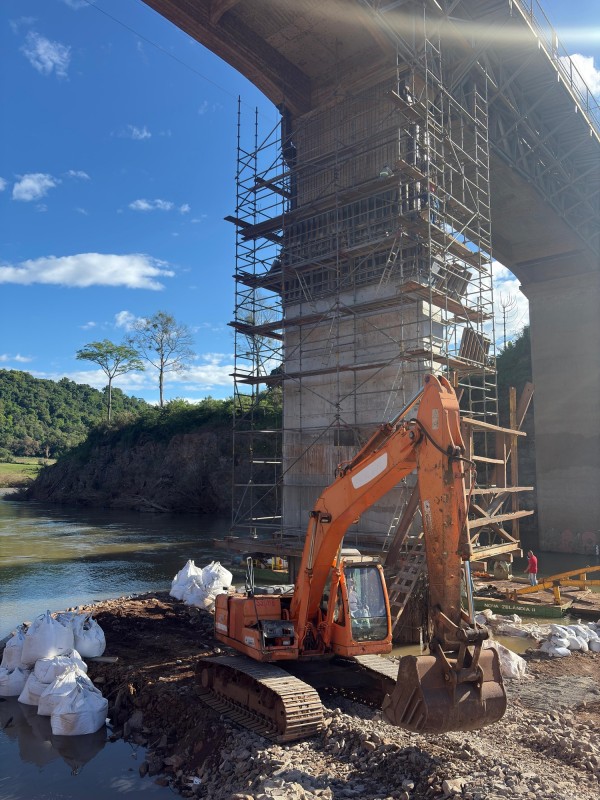 Foto mostra máquina trabalhando no pilar da ponte. 